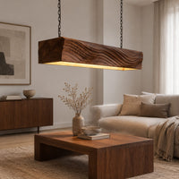 Linear wooden pendant light with wave carved sides and a glowing underside in a Scandinavian living room with white walls