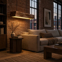 Linear wooden pendant light with wave carved sides and a glowing underside in an industrial loft living room with exposed brick