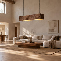 Linear wooden pendant light with wave carved sides and a glowing underside in a bright open plan living room