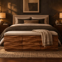 Bench with a padded seat and three wave carved front panels in a dark bedroom at golden hour