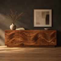 Long sideboard with deep wave carving across the full front in a dark studio against a charcoal plaster wall