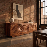Long sideboard with deep wave carving across the full front in an industrial loft dining room with exposed brick