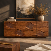Corner detail of wave carved wooden sideboard with four relief panels on a plinth base beside wood, brass and linen samples