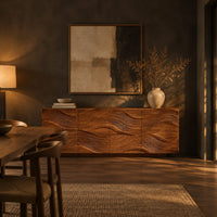 Wave carved wooden sideboard with four relief panels on a plinth base in a dark dining room at golden hour