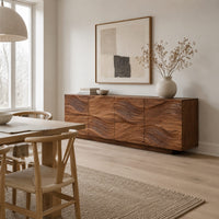 Wave carved wooden sideboard with four relief panels on a plinth base in a Scandinavian dining room with white walls
