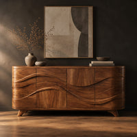 Wave carved sideboard with four front panels and short tapered feet in a dark studio against a charcoal plaster wall