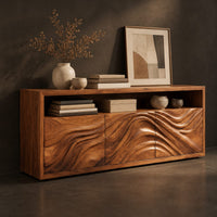 Corner detail of low sideboard with three carved wave panels and an open display shelf above beside wood, brass and linen samples