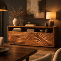 Low sideboard with three carved wave panels and an open display shelf above in a dark dining room at golden hour