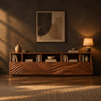 Low tv stand with wave carved front panels and a row of open cubbies in a dark living room at golden hour