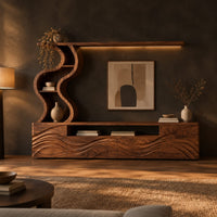 Long wood media cabinet with wave carved fronts and an s shaped shelf tower in a dark living room at golden hour