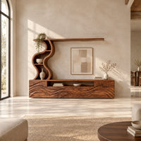 Long wood media cabinet with wave carved fronts and an s shaped shelf tower in a bright open plan living room