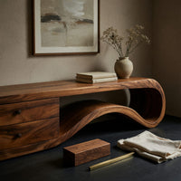 Corner detail of wave end TV stand with a two drawer block beside wood, brass and linen samples