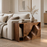 Boxy side table with a carved wave front and an open book slot in a Scandinavian living room with white walls