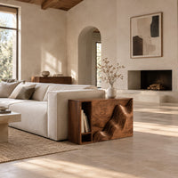 Boxy side table with a carved wave front and an open book slot in a bright open plan living room