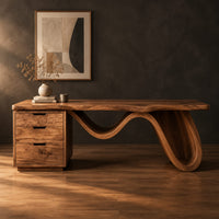 Desk with a thick slab top, three drawer pedestal and a wave shaped leg in a dark studio against a charcoal plaster wall