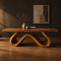 Long dining table on a single sculpted wave ribbon base in a dark studio against a charcoal plaster wall