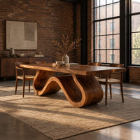 Long dining table on a single sculpted wave ribbon base in an industrial loft dining room with exposed brick