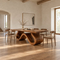 Long dining table on a single sculpted wave ribbon base in a bright open plan dining room