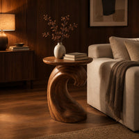 Side table with a wave shaped pedestal and a circular top in an evening living room with walnut wall paneling