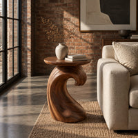 Side table with a wave shaped pedestal and a circular top in an industrial loft living room with exposed brick