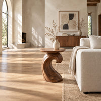 Side table with a wave shaped pedestal and a circular top in a bright open plan living room