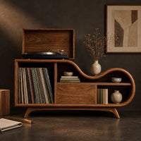 Corner detail of low wooden record player stand with a wavy top and open record bay beside wood, brass and linen samples