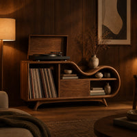 Low wooden record player stand with a wavy top and open record bay in an evening living room with walnut wall paneling