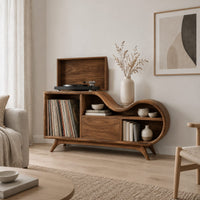 Low wooden record player stand with a wavy top and open record bay in a Scandinavian living room with white walls