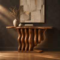Console table with a base of wavy wood columns on an oval foot in a dark studio against a charcoal plaster wall