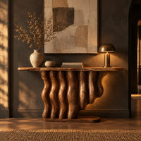 Console table with a base of wavy wood columns on an oval foot in a dark entryway at golden hour