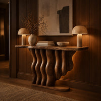 Console table with a base of wavy wood columns on an oval foot in an evening entryway with walnut wall paneling