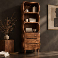 Corner detail of tall bathroom cabinet with three wavy open shelves and three drawers beside wood, brass and linen samples