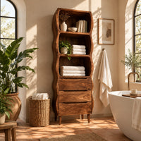Tall bathroom cabinet with three wavy open shelves and three drawers in a bright bathroom with arched windows and plants
