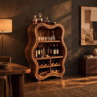 Tall wavy outline bar cabinet with open shelves and four wine cubbies in a dark dining room at golden hour