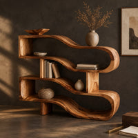 Corner detail of wavy ribbon bookshelf with open shelves joined by chunky square posts beside wood, brass and linen samples
