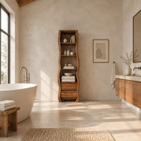Tall narrow cabinet with wavy sides, four open shelves and two drawer fronts below in a bright open plan bathroom
