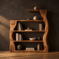 Bookshelf with wavy wood sides, open shelves and a top ledge in a dark studio against a charcoal plaster wall