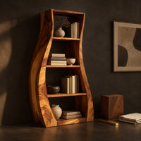 Corner detail of tall bookshelf with wavy side panels and open shelves beside wood, brass and linen samples