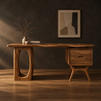 Wooden desk with an oval leg frame, a wavy top and a side pedestal in a dark studio against a charcoal plaster wall