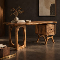 Corner detail of wooden desk with an oval leg frame, a wavy top and a side pedestal beside wood, brass and linen samples