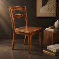 Corner detail of wooden chair with two wavy back slats and tapered legs beside wood, brass and linen samples