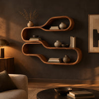 Wall shelf of two stacked flowing loops joined by a wavy ledge in a dark living room at golden hour