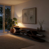 Low TV console with carved web supports between shelves in an evening room lit by two lamps