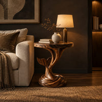 Side table with a carved whale tail on a spiral stem and coiled base in a dark living room at golden hour