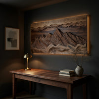 Wide landscape wall relief with layered sky bands above a desk in a dark study corner