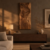 Tall wooden wall art panel with carved wildflowers and a wavy edge above a low console in an evening living room