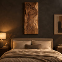 Tall wooden wall art panel with carved wildflowers and a wavy edge above a bed in a dusk lit bedroom