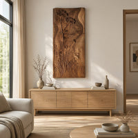 Tall wooden wall art panel with carved wildflowers and a wavy edge above a light oak sideboard in daylight