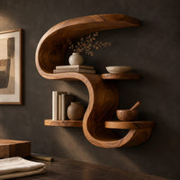 Corner detail of sculpted wall shelf in an s shape with a hooked top and small ledges beside wood, brass and linen samples
