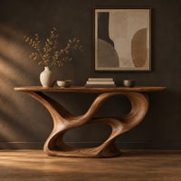 Console table with a winding ribbon base and a long tapered top in a dark studio against a charcoal plaster wall